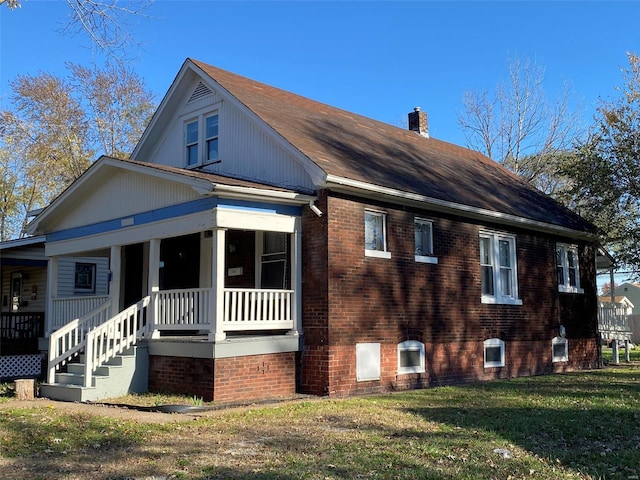 view of side of property featuring a lawn and covered porch