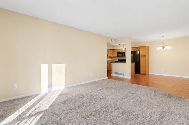 unfurnished living room with a chandelier and light hardwood / wood-style flooring