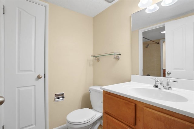 bathroom featuring tiled shower, vanity, a textured ceiling, and toilet