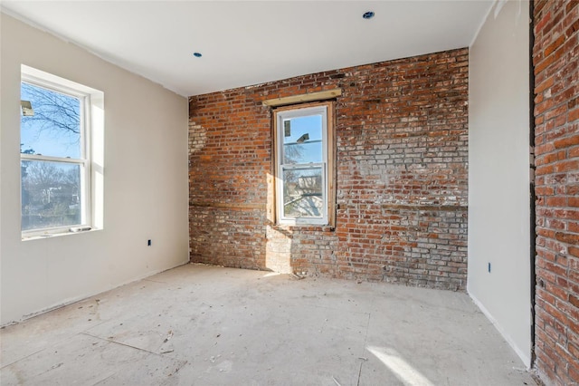 unfurnished room with a healthy amount of sunlight and brick wall