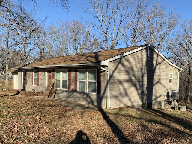 view of side of home featuring cooling unit and a yard