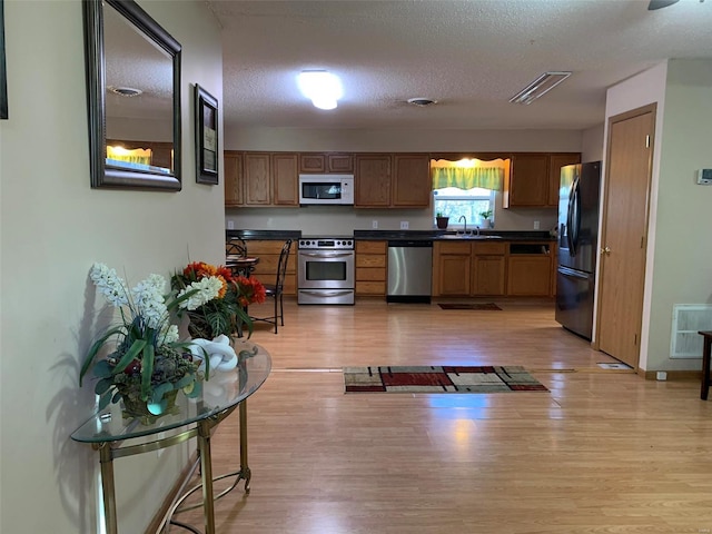 kitchen featuring a textured ceiling, light hardwood / wood-style floors, sink, and stainless steel appliances