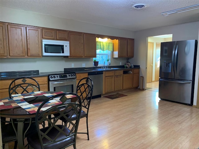 kitchen featuring a textured ceiling, sink, stainless steel appliances, and light hardwood / wood-style flooring