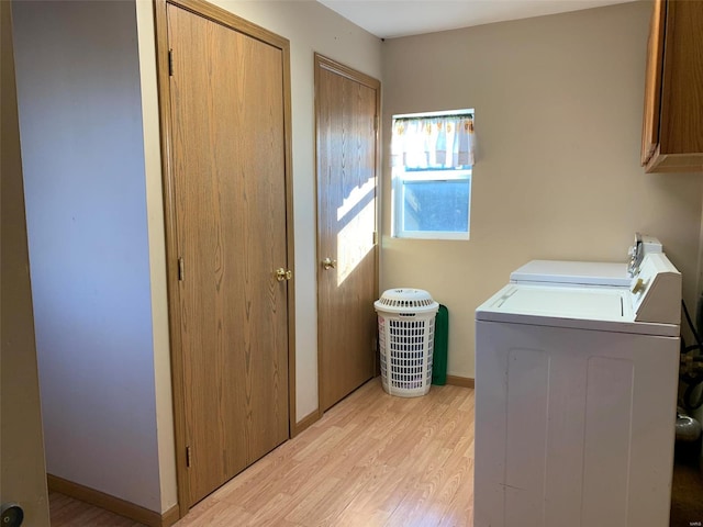 laundry room with washing machine and dryer, cabinets, and light hardwood / wood-style floors