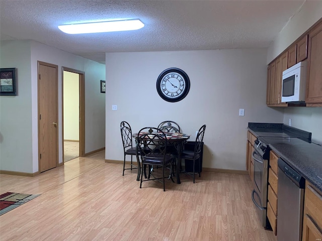 kitchen with a textured ceiling, stainless steel appliances, and light hardwood / wood-style flooring