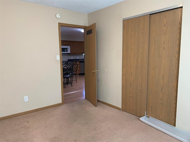 unfurnished bedroom featuring a closet, light colored carpet, and a textured ceiling