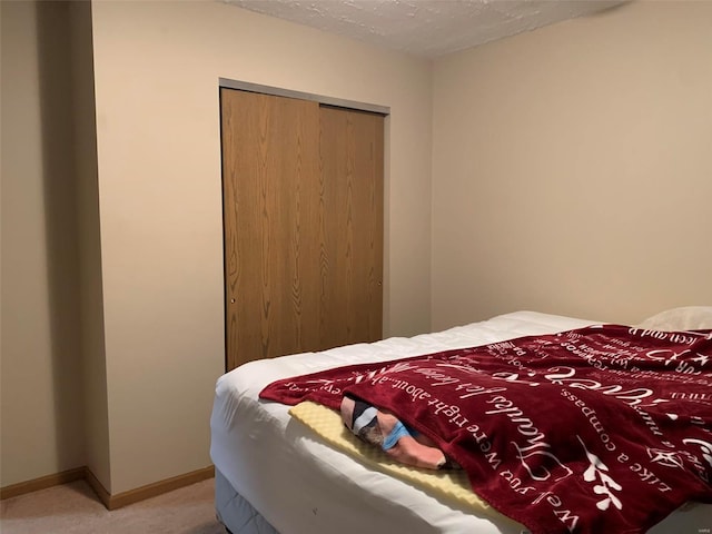 carpeted bedroom featuring a textured ceiling and a closet