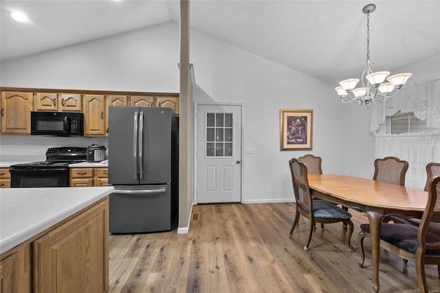 kitchen with vaulted ceiling, black appliances, decorative light fixtures, a chandelier, and light hardwood / wood-style floors