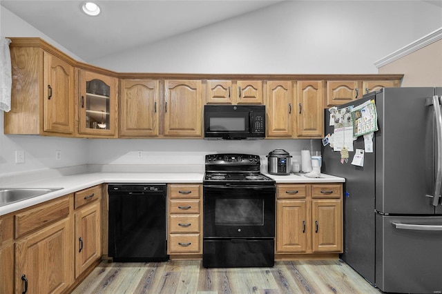 kitchen with sink, black appliances, lofted ceiling, and light hardwood / wood-style floors