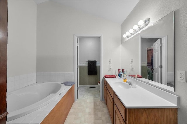 bathroom featuring vanity, a relaxing tiled tub, and lofted ceiling