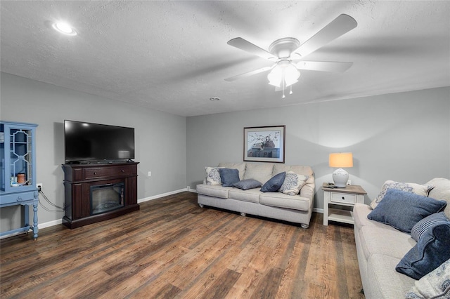 living room with a textured ceiling, dark hardwood / wood-style floors, and ceiling fan