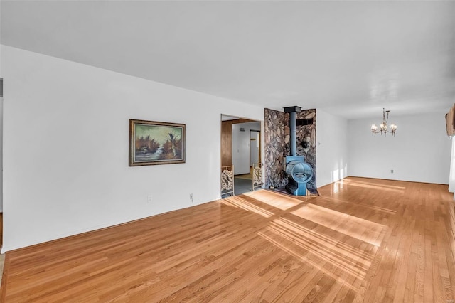 unfurnished living room with hardwood / wood-style floors, a chandelier, and a wood stove