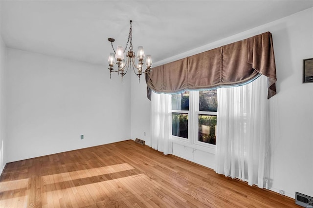 spare room featuring hardwood / wood-style flooring and a chandelier