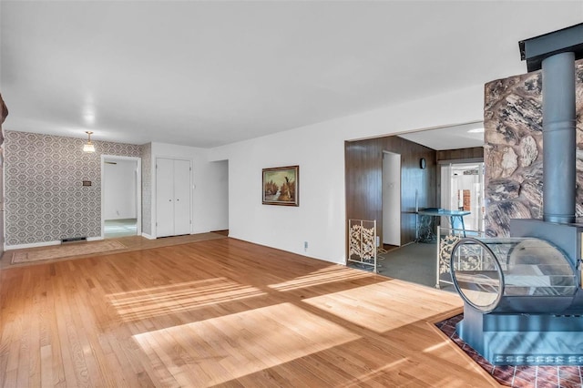 unfurnished living room featuring wood-type flooring and a wood stove