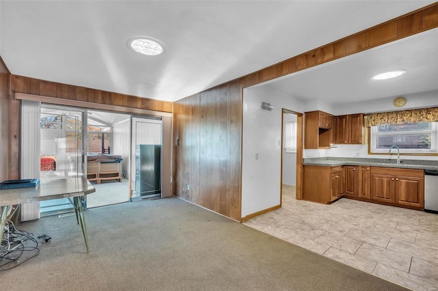 kitchen with light colored carpet, sink, a healthy amount of sunlight, and wooden walls