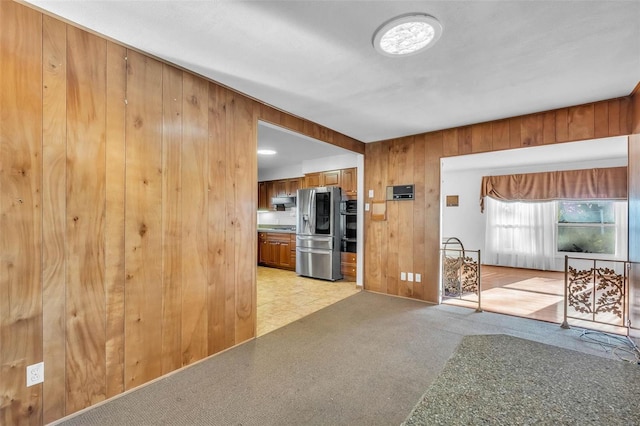 unfurnished living room with light carpet and wooden walls