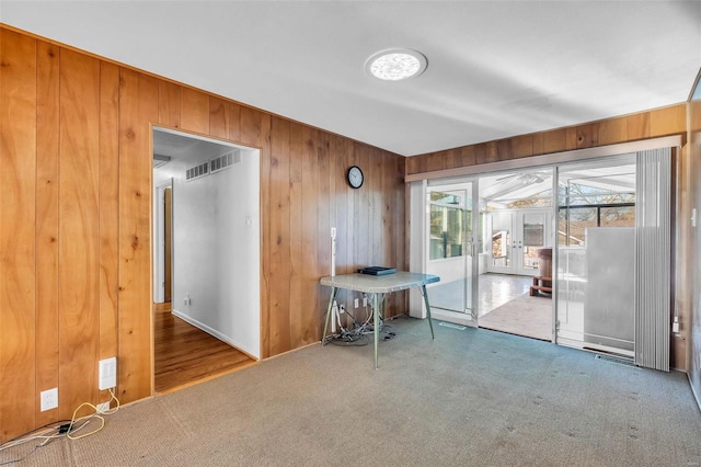 carpeted spare room with wooden walls