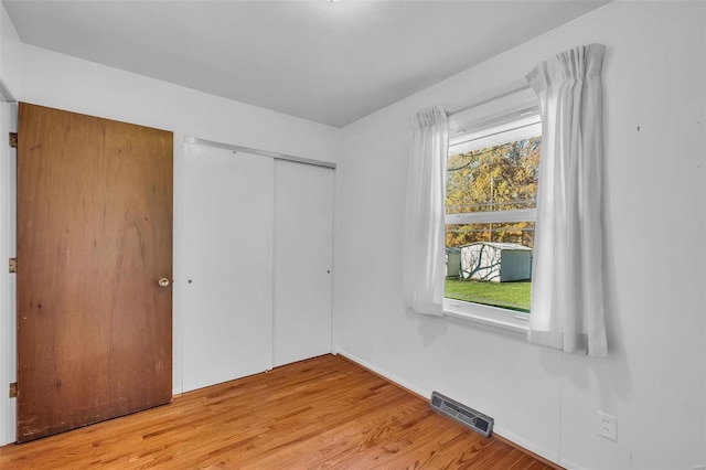 unfurnished bedroom featuring multiple windows, a closet, and light wood-type flooring