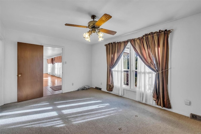 empty room with ceiling fan and light carpet