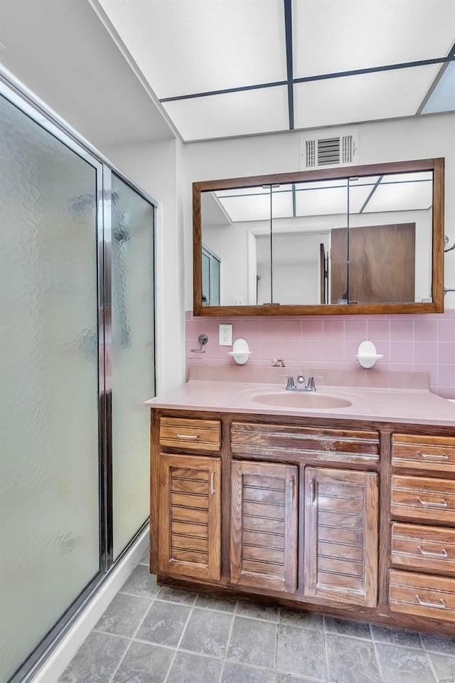 bathroom with decorative backsplash, vanity, and a shower with door