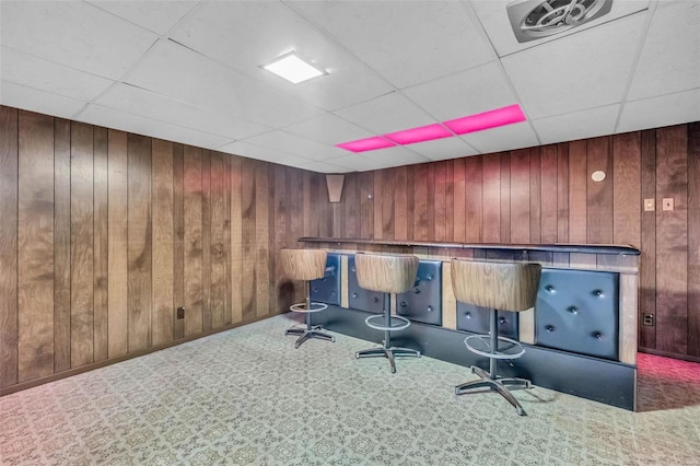 bar featuring carpet, wood walls, and a paneled ceiling