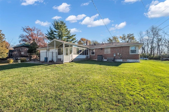 rear view of property with central AC, a yard, and a sunroom