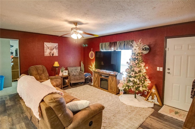 living room featuring ceiling fan, dark hardwood / wood-style flooring, and a textured ceiling