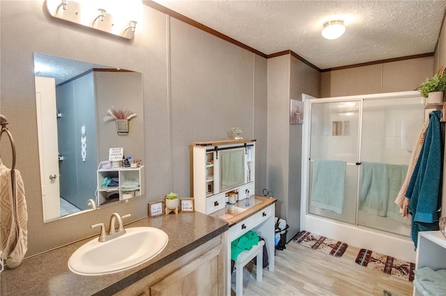 bathroom featuring hardwood / wood-style floors, a textured ceiling, walk in shower, and ornamental molding