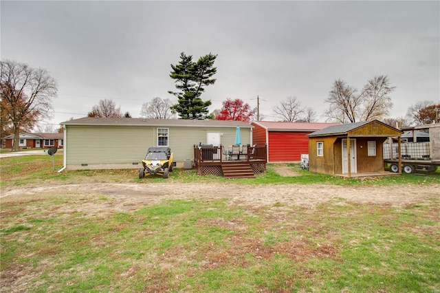 rear view of property featuring an outbuilding, a deck, and a lawn