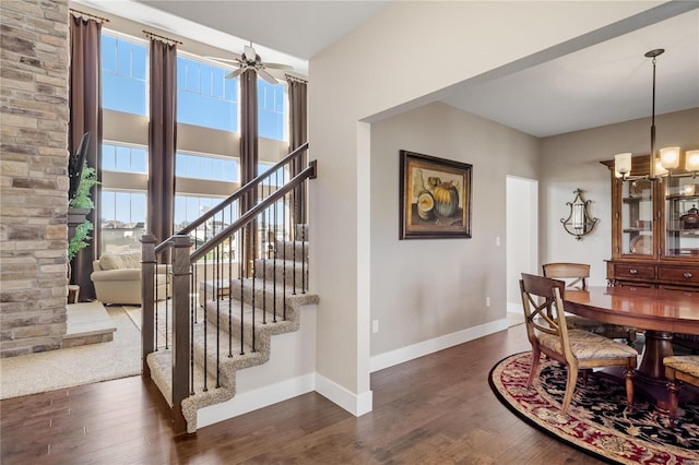 dining area with ceiling fan with notable chandelier, dark wood-type flooring, and a healthy amount of sunlight