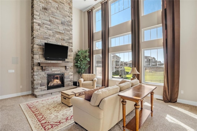 carpeted living room featuring a high ceiling and a stone fireplace