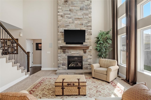 carpeted living room featuring a fireplace and a towering ceiling