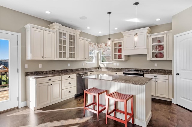 kitchen featuring a kitchen bar, appliances with stainless steel finishes, dark hardwood / wood-style flooring, decorative light fixtures, and a center island