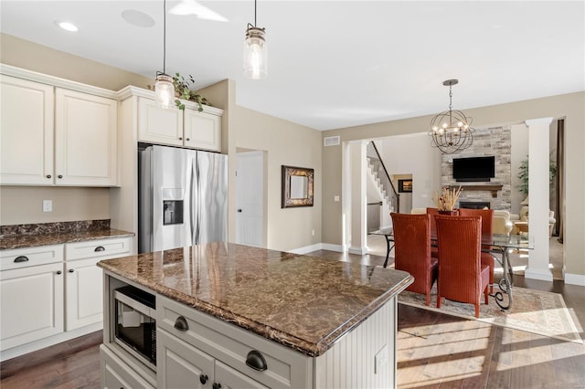 kitchen featuring a center island, dark hardwood / wood-style flooring, dark stone countertops, a fireplace, and appliances with stainless steel finishes