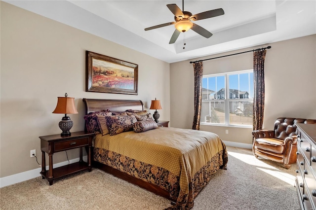 bedroom with a tray ceiling, ceiling fan, and light carpet