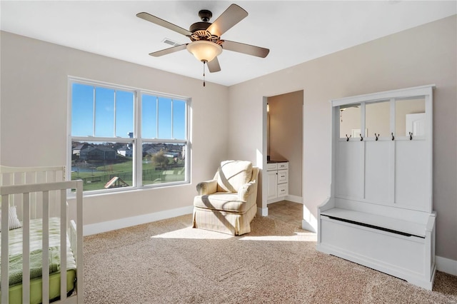 carpeted bedroom featuring ceiling fan and a crib