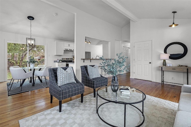 living room with a notable chandelier, vaulted ceiling with beams, and light hardwood / wood-style floors