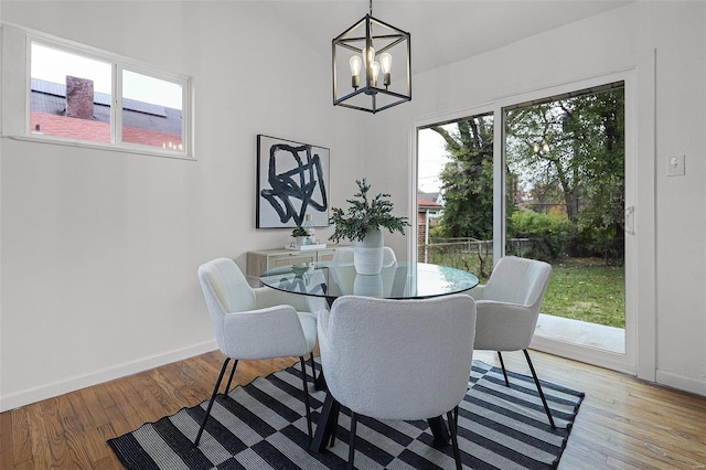 dining space with a wealth of natural light, light hardwood / wood-style flooring, and a notable chandelier