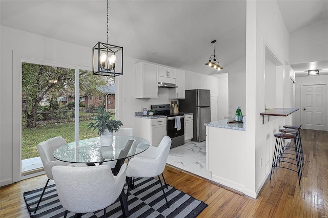 dining space featuring light hardwood / wood-style floors, lofted ceiling, and a wealth of natural light