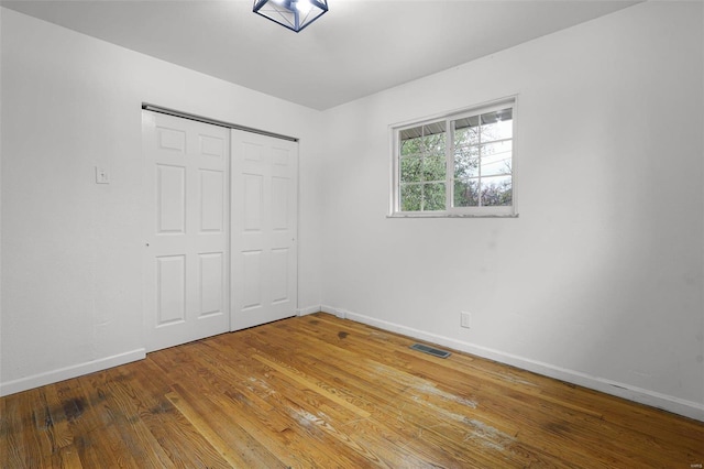 unfurnished bedroom featuring a closet and hardwood / wood-style floors