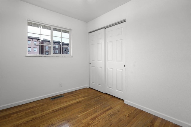 unfurnished bedroom with dark hardwood / wood-style flooring and a closet