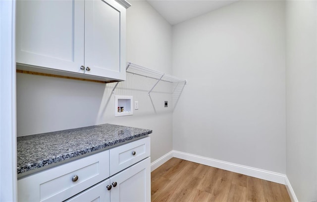 clothes washing area with hookup for an electric dryer, hookup for a washing machine, light hardwood / wood-style flooring, and cabinets