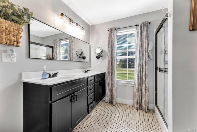 bathroom featuring plenty of natural light, a shower with door, and vanity