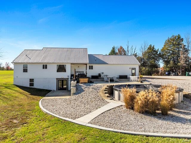 back of property featuring a yard, a patio, an outdoor hangout area, and a covered pool