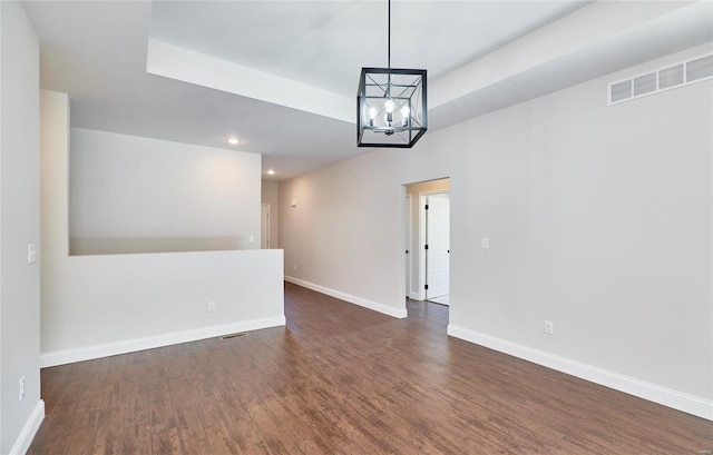 spare room featuring dark hardwood / wood-style flooring and an inviting chandelier