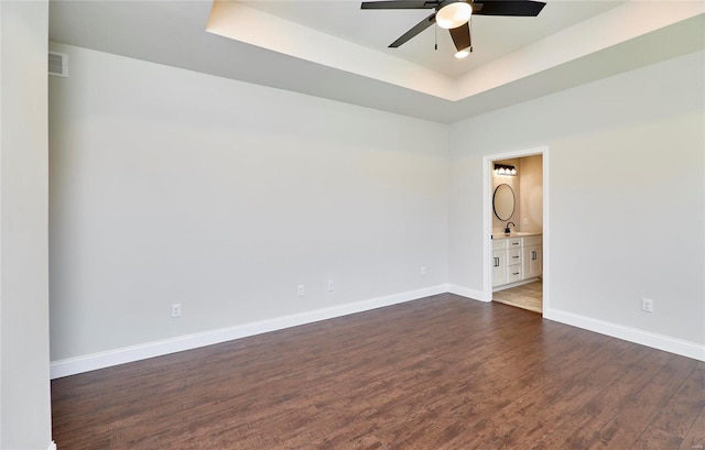 unfurnished room featuring dark hardwood / wood-style floors, ceiling fan, a raised ceiling, and sink