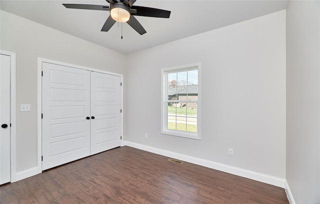 unfurnished bedroom with ceiling fan and dark wood-type flooring