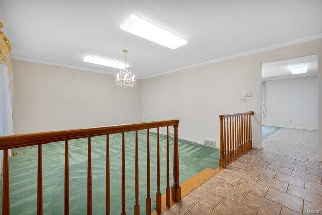 hallway featuring an inviting chandelier, light tile patterned floors, and ornamental molding