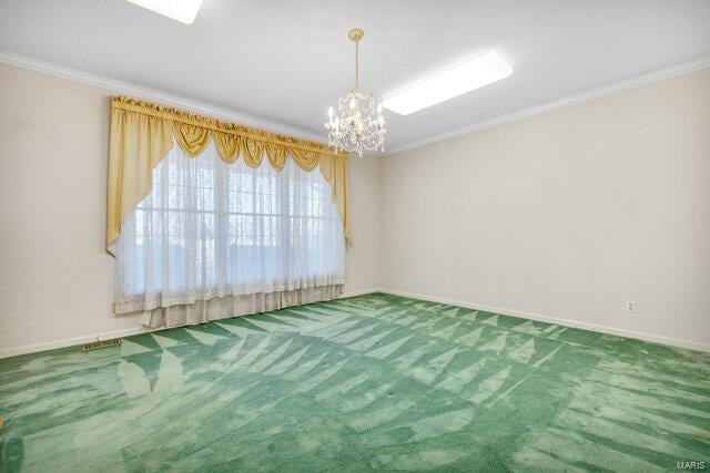 spare room featuring carpet floors, ornamental molding, and a chandelier