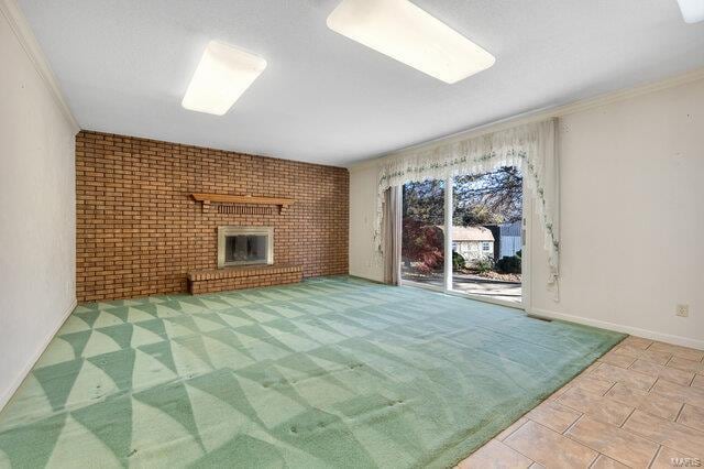 unfurnished living room with a fireplace, ornamental molding, and brick wall